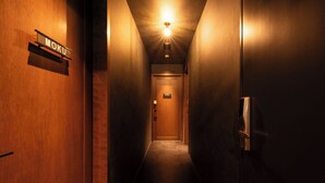 A narrow, dimly lit hallway with wooden walls and a door labeled 'MOKU' at the end.