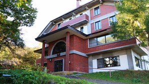 A multi-story building with a prominent arched entrance, brick facade, and large windows. - Petit Hotel Zontakku (Ueda)