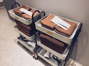 Deux chariots en métal, avec des serviettes marron et des draps blancs, probablement destinés à un hôtel.