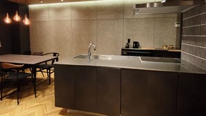 Una cocina moderna con una isla central, un lavamanos de acero inoxidable e iluminación colgante.
