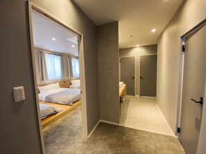 Une chambre d’hôtel comprenant un lit, une salle de bain et un couloir menant à une porte.