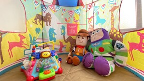 Una estructura en forma de tienda de campaña decorada con coloridos adornos de animales y personajes, un tren de juguete y peluches.