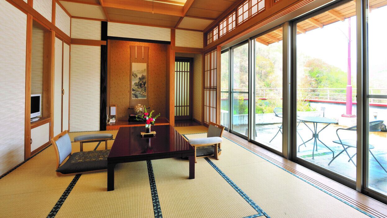 Una habitación japonesa tradicional con suelo de tatami, una mesa baja, cojines y puertas correderas.