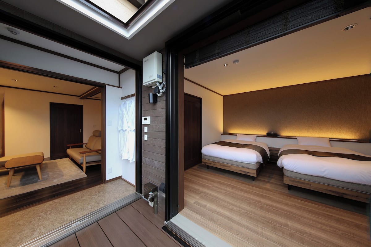 Une chambre d’hôtel moderne dotée d’une lucarne, de deux lits, d’un coin salon et d’une salle de bain.