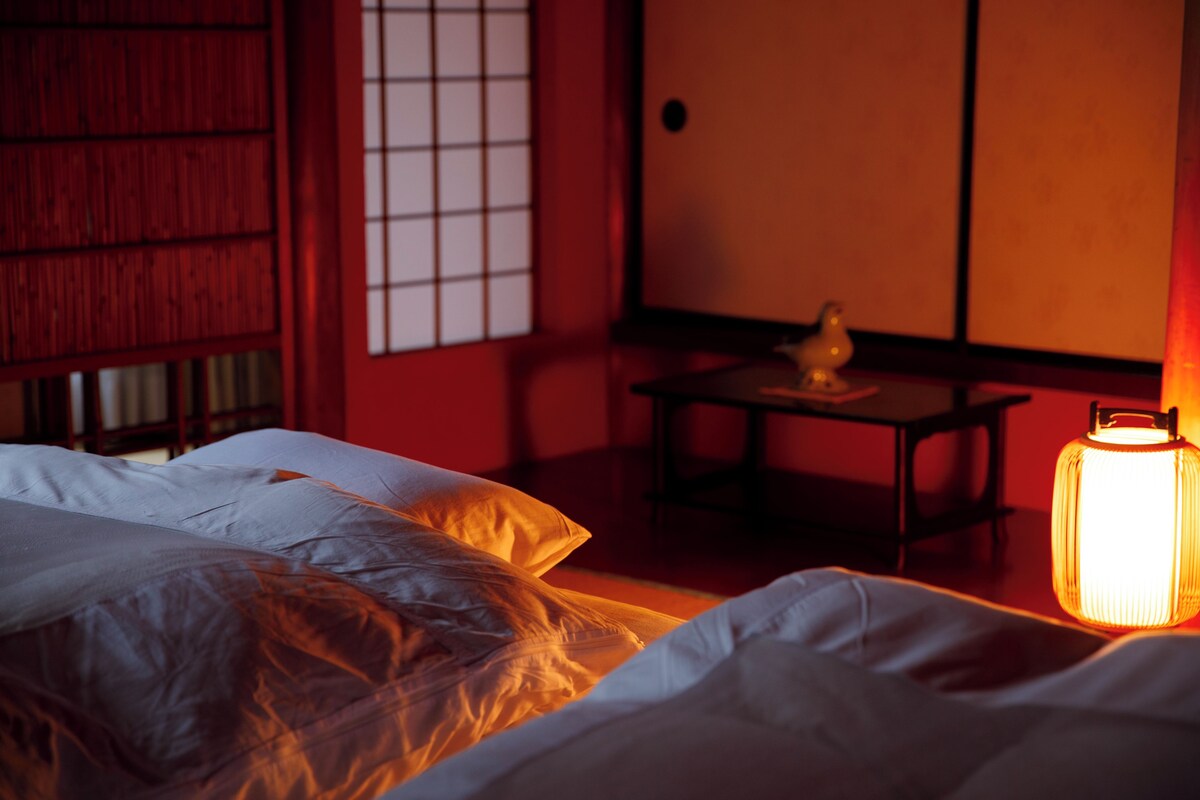 A room with a bed, a table with a lamp, and a traditional sliding door.