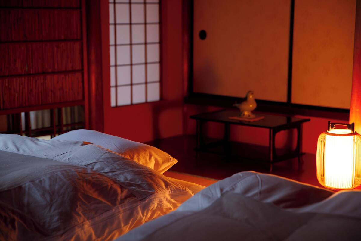 Une pièce comprenant un lit, une table avec une lampe et une porte coulissante traditionnelle.