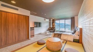Una habitación de hotel moderna con una cama grande, un sofá, un televisor y vistas a la montaña.