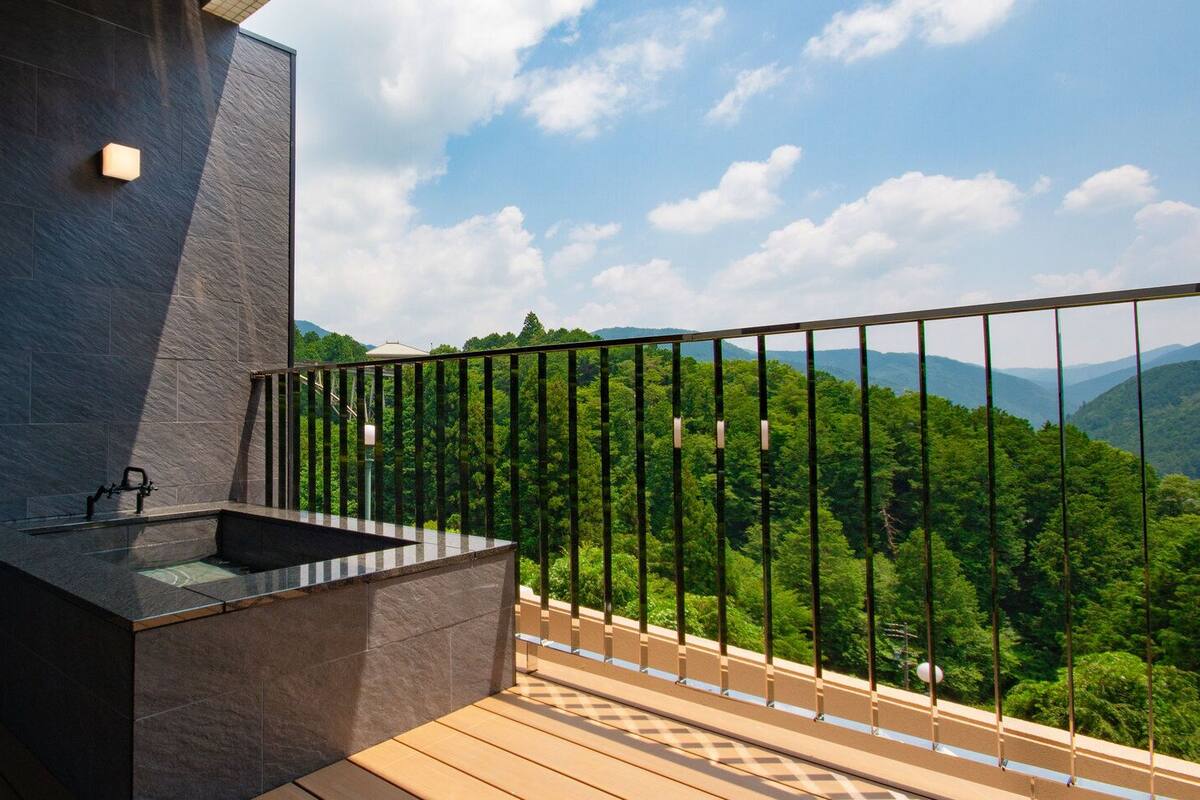 A balcony with a built-in sink and a view of a forested mountain range.