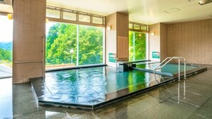 Una piscina interior con ventanales amplios, un banco y un puesto de socorrista.