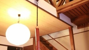 A room with a wooden staircase, a hanging lamp, and a desk with a computer.
