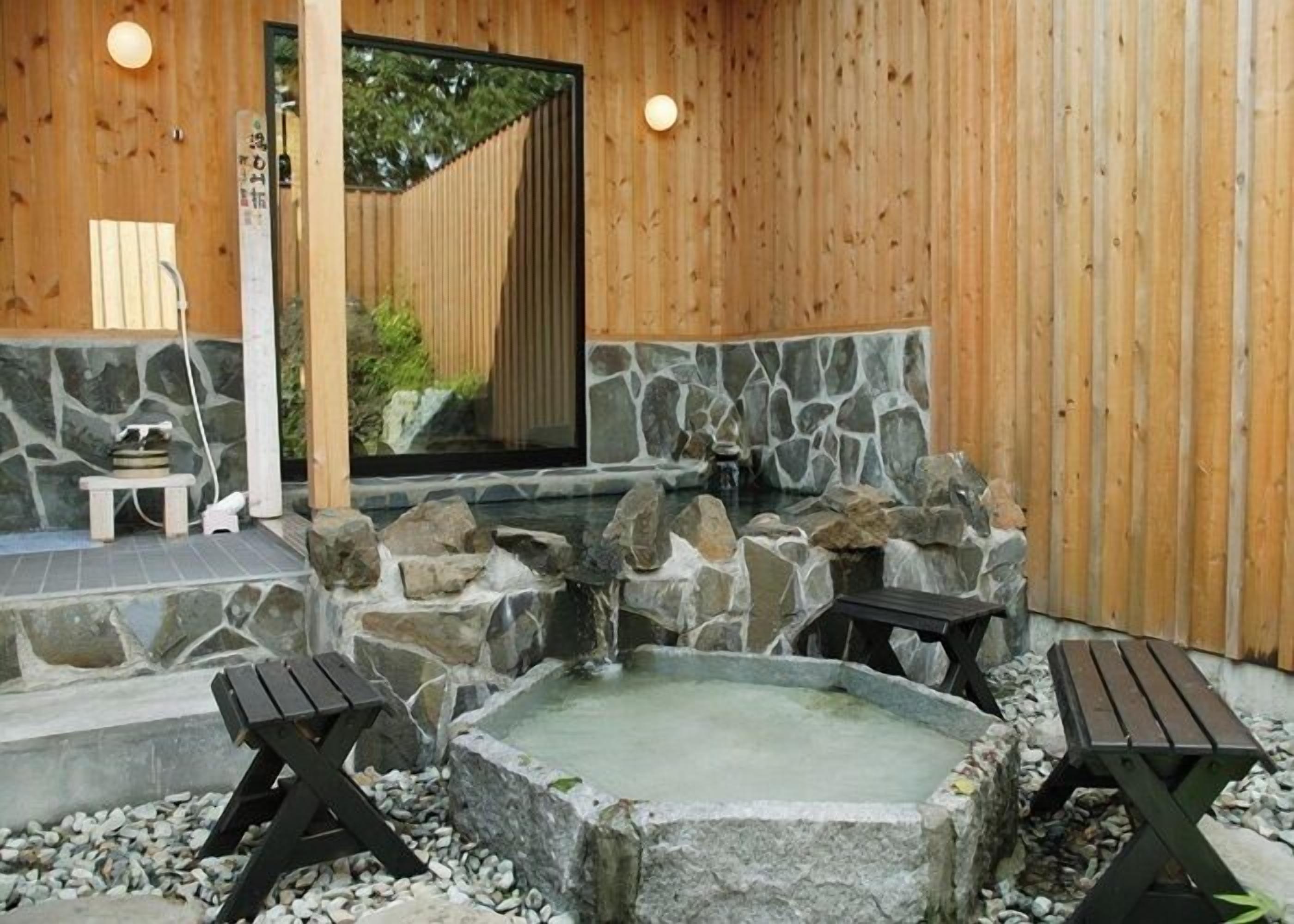 Ein Holz-Spa mit einer Stein-Whirlpool-Badewanne, zwei Holz-Bänken und einem kleinen Tisch.