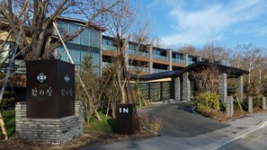 Un edificio moderno con fachada de vidrio, entrada de ladrillo y señalización en un idioma extranjero.