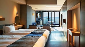Una habitación de hotel moderna con una cama grande, un área de descanso con vistas y un balcón.