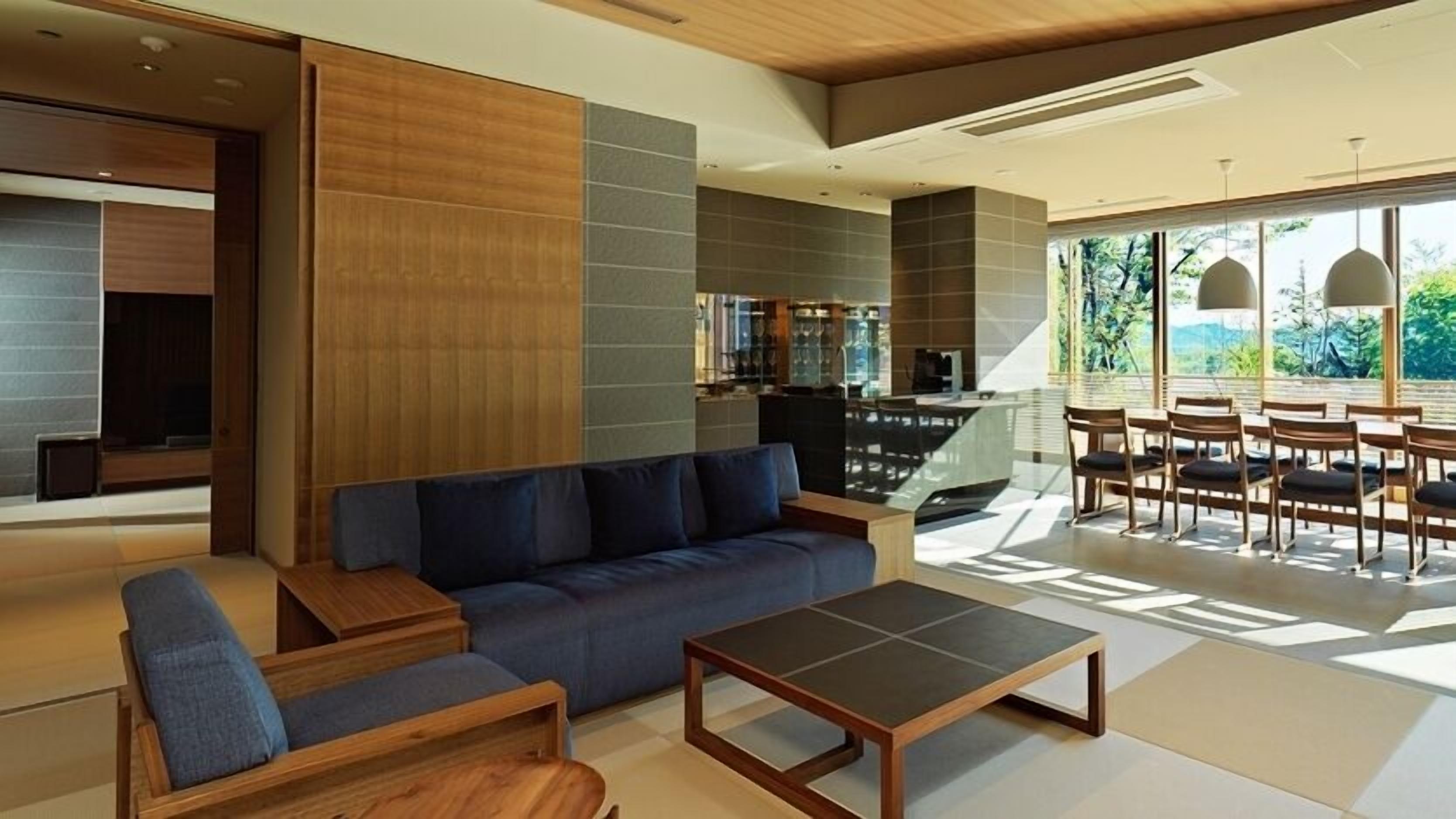 A modern living room with a sofa, coffee table, and dining area with chairs.