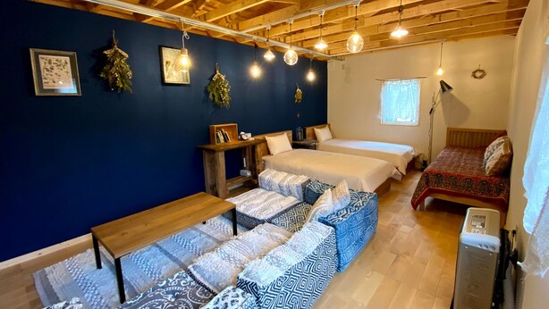 A cozy room with a wooden ceiling, two beds, a bench, and a small table.