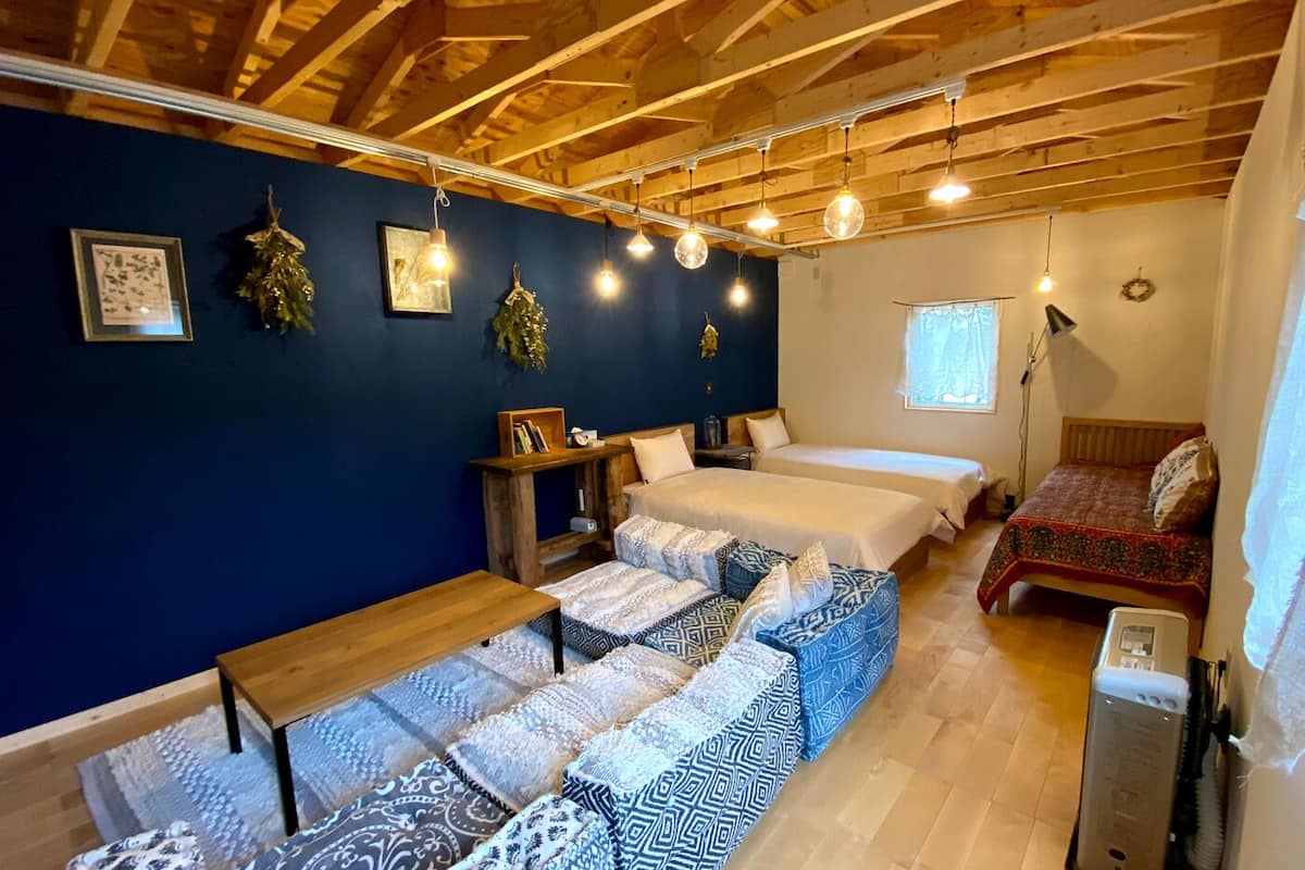 Ein gemütliches Zimmer mit Holzbalkendecke, zwei Betten, einer Bank und einem kleinen Tisch.