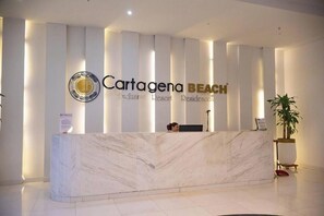 Ein Empfangsschalter mit Marmorplatte und einem Schild mit der Aufschrift 'Cartagena BEACH Exclusive Resort Residences'.