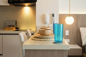 Eine moderne Küche mit Esstisch, Stühlen, einer blauen Glasvase und einer Wandleuchte.