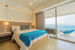Ein modernes Hotelzimmer mit einem großen Bett, einem Balkon mit Sitzgelegenheit und Blick auf das Meer.