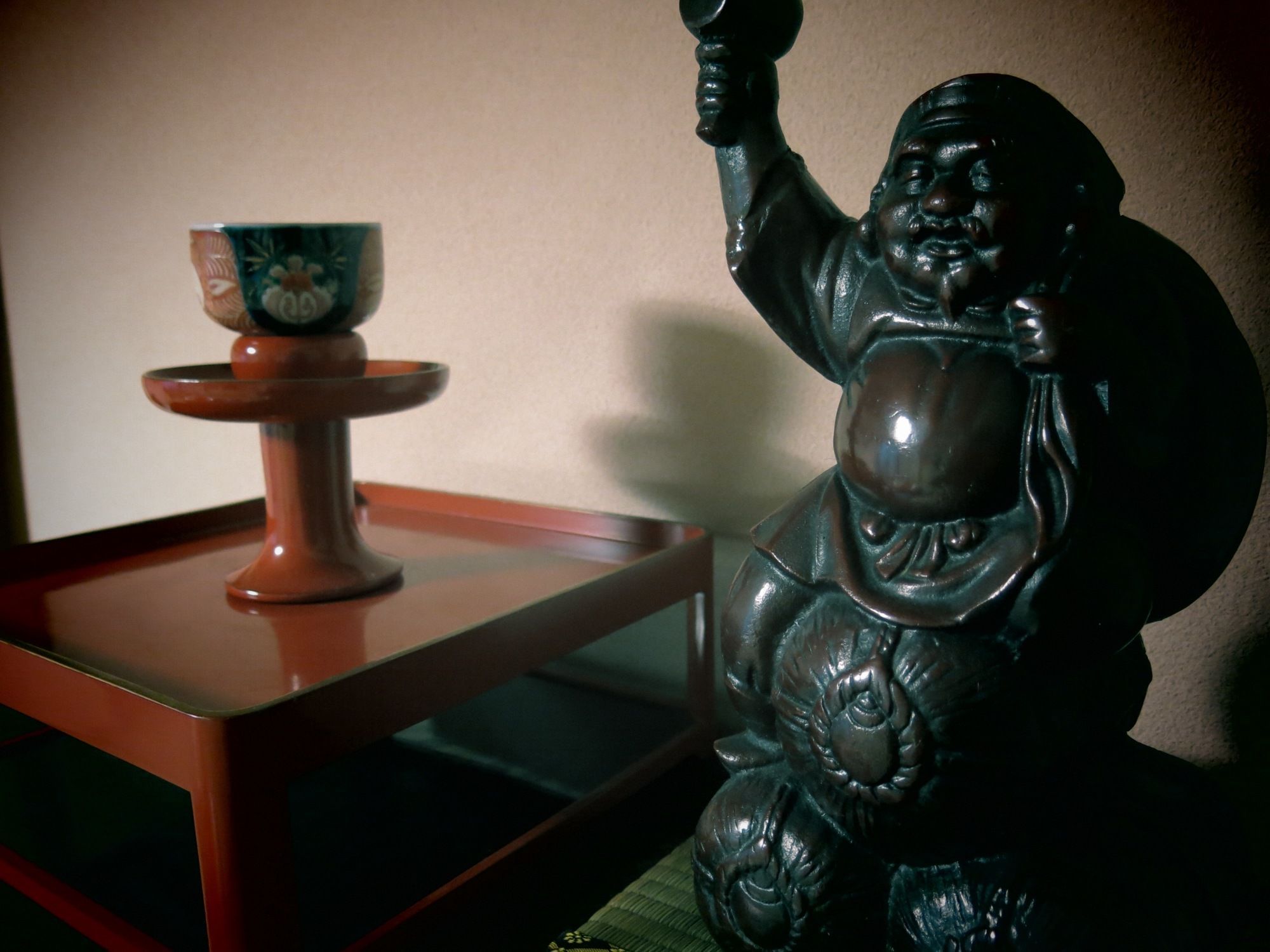 A statue of a figure holding a cup on a wooden table.