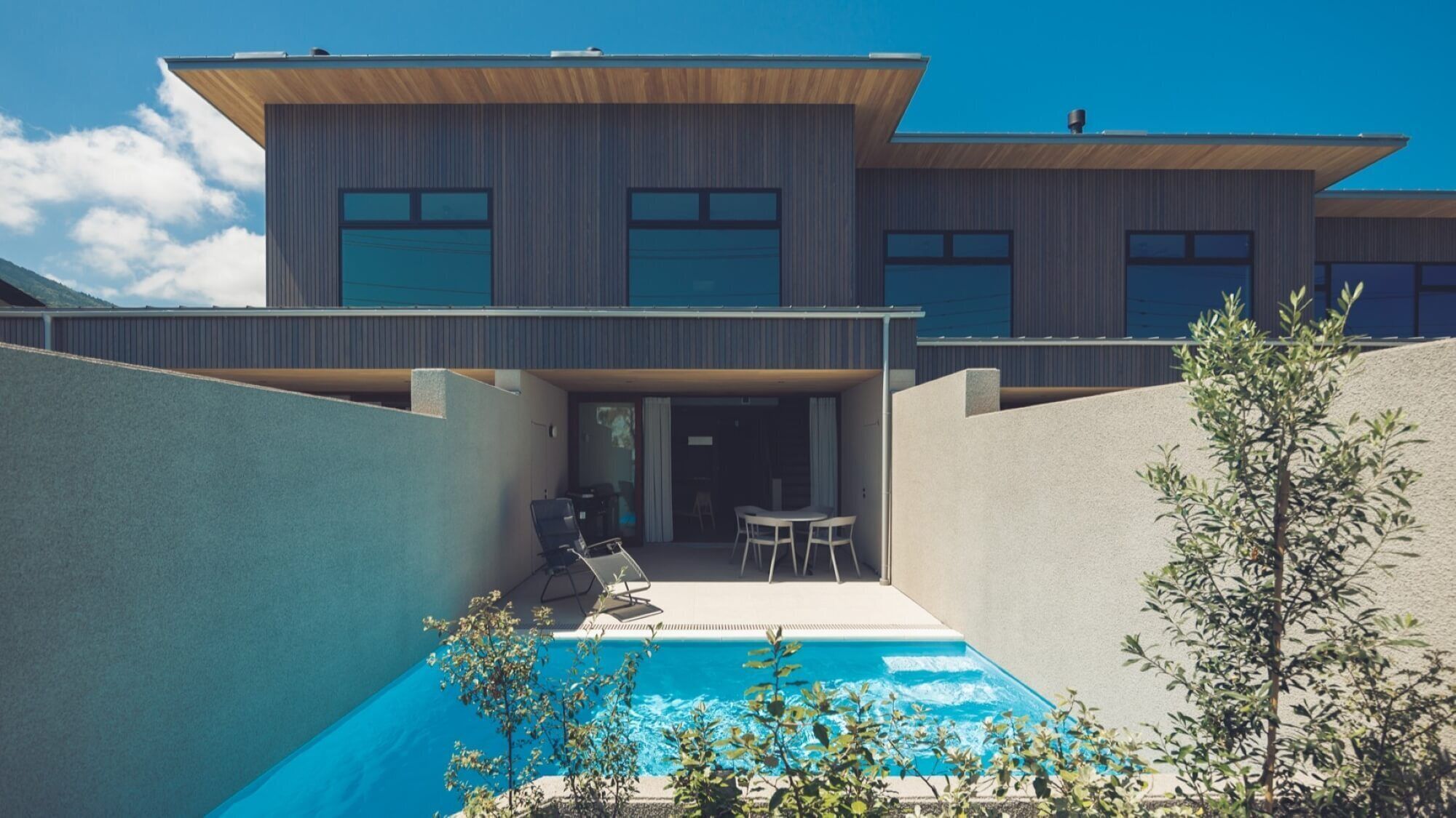 Una casa moderna con piscina, mobiliario exterior y vistas al cielo.