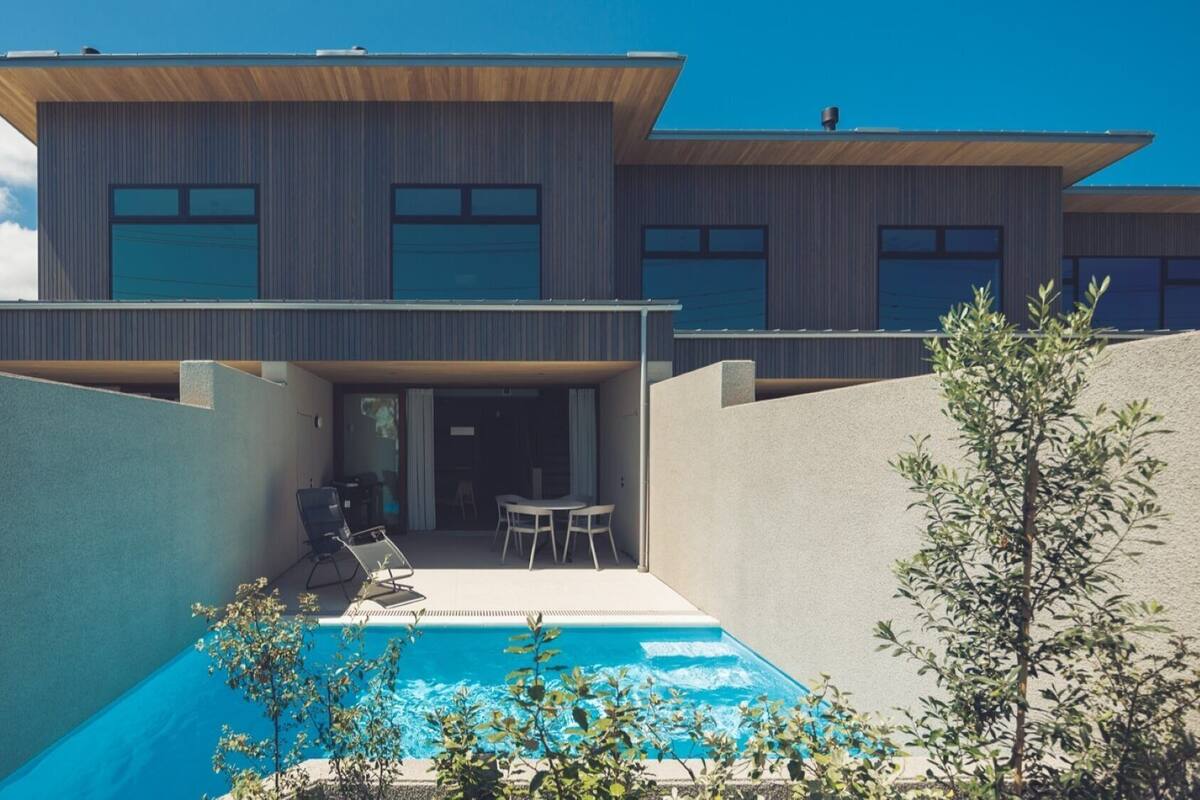 Una casa moderna con piscina, mobiliario exterior y vistas al cielo.