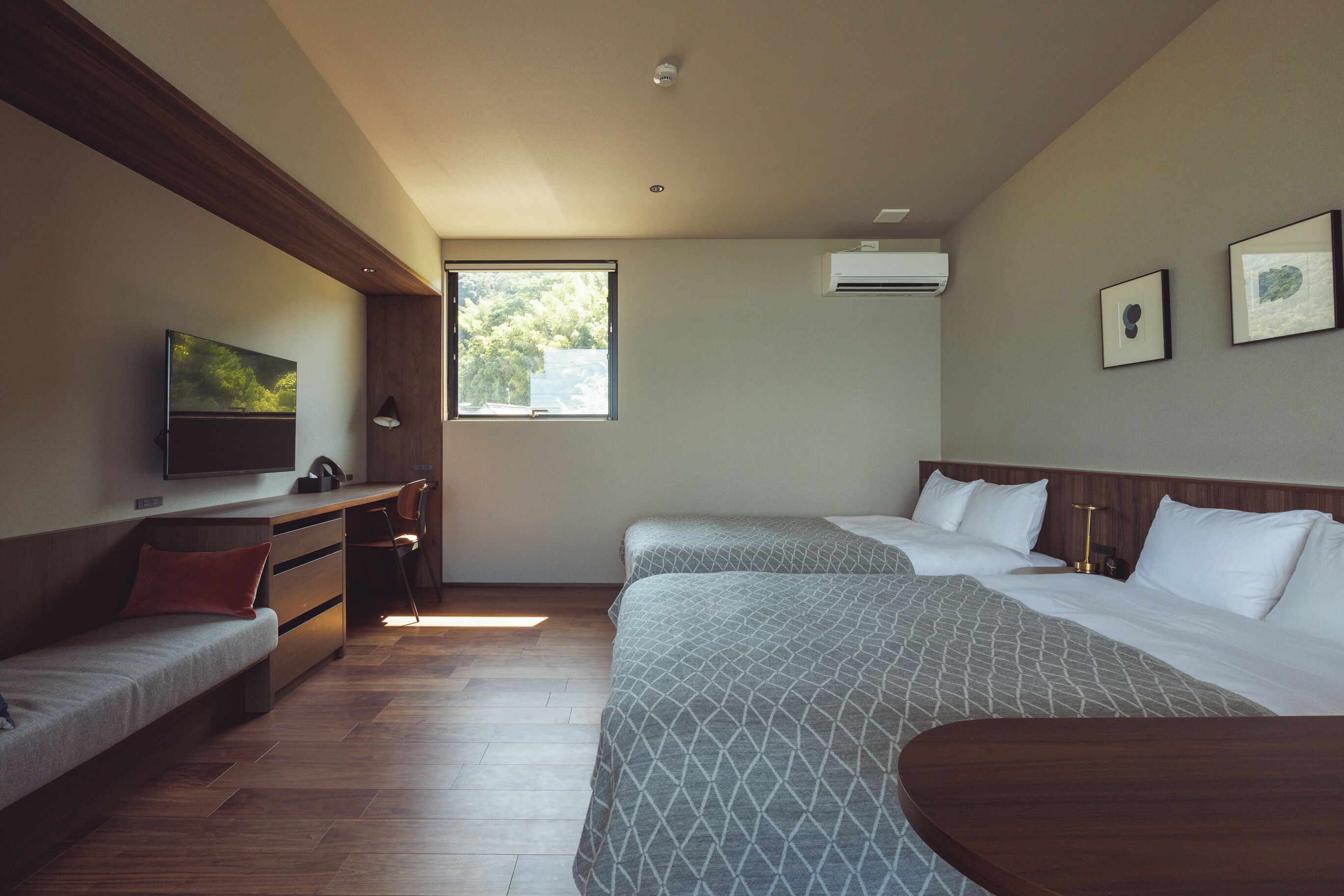 A hotel room with a bed, a sofa, a desk, a TV, and a window.