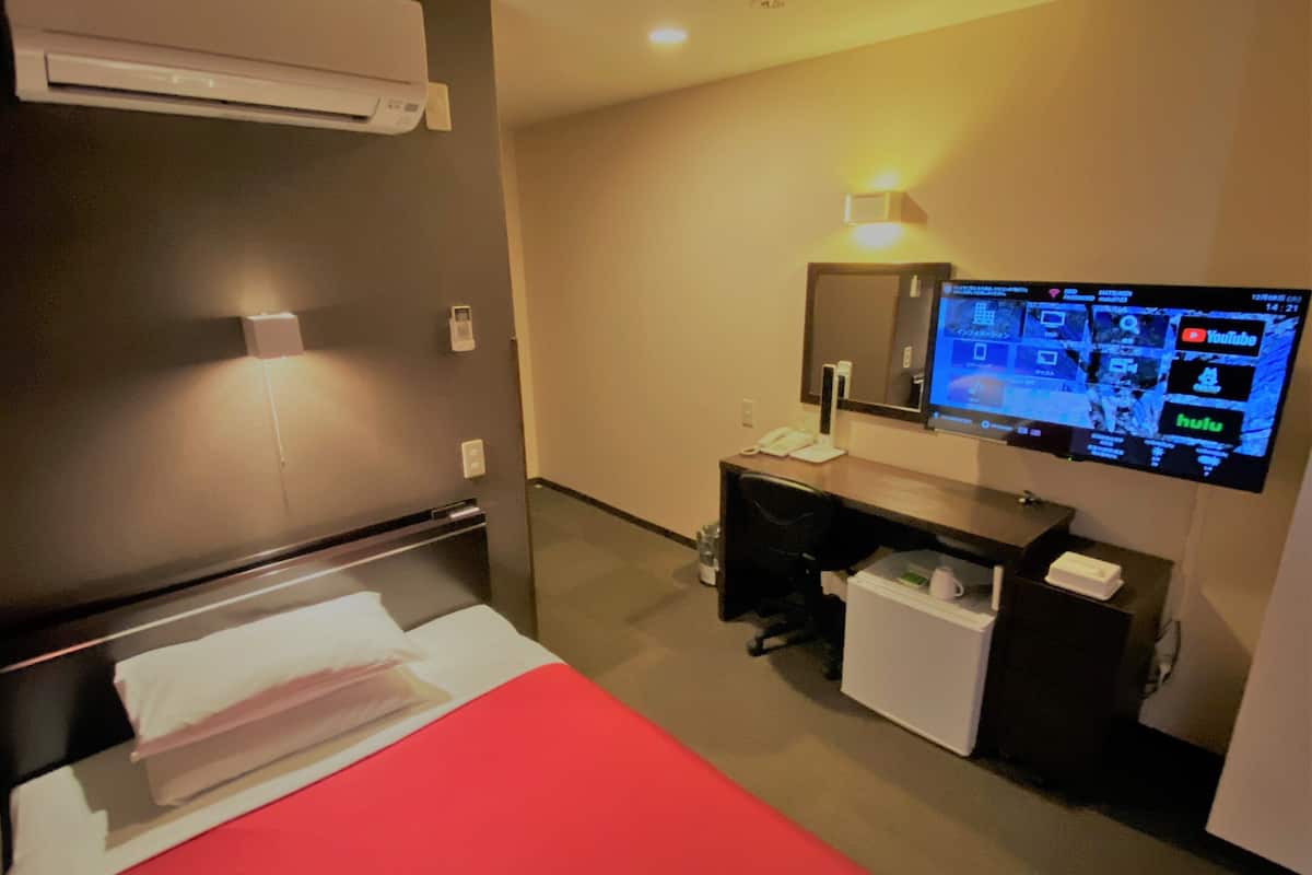 Une chambre d’hôtel équipée d’un lit, d’un bureau et d’un téléviseur à écran plat fixé au mur.