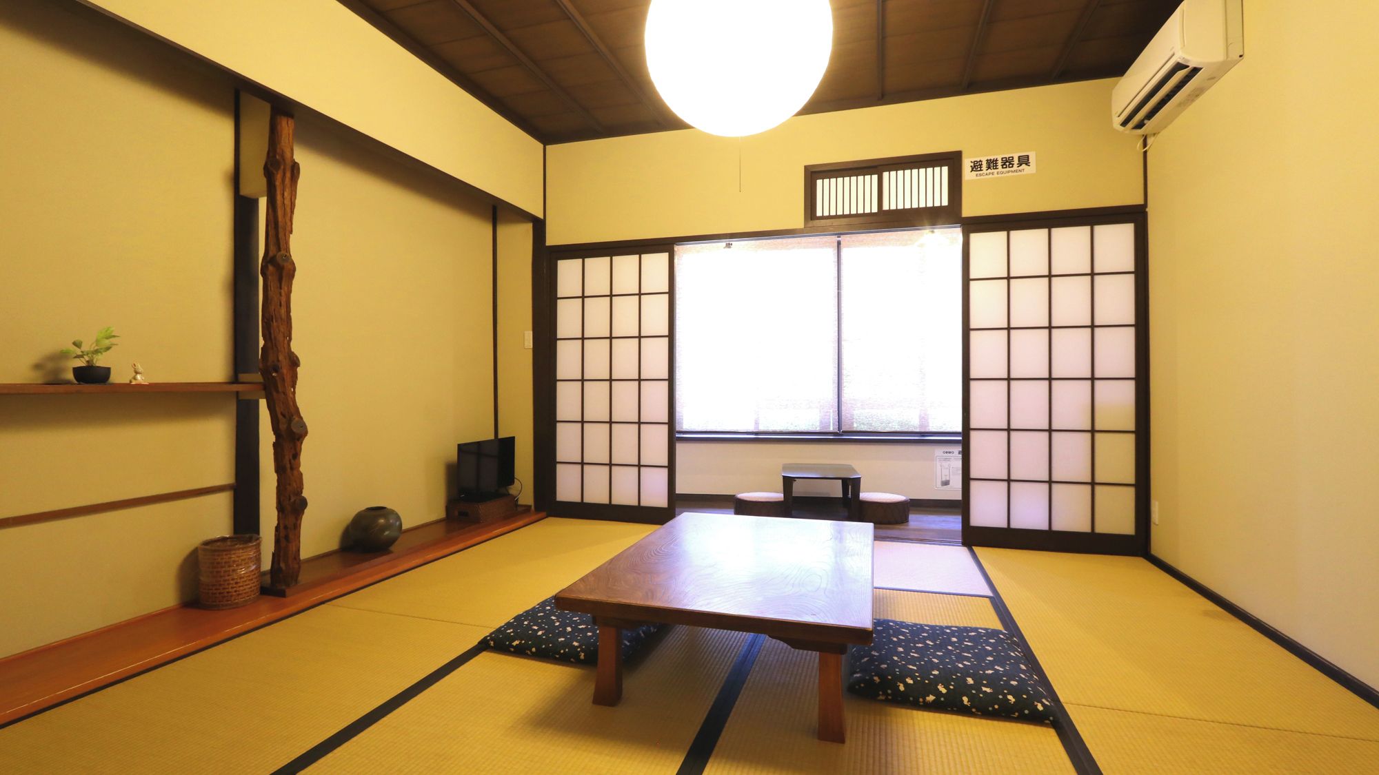 A traditional Japanese room with tatami flooring, a low table, and sliding doors.