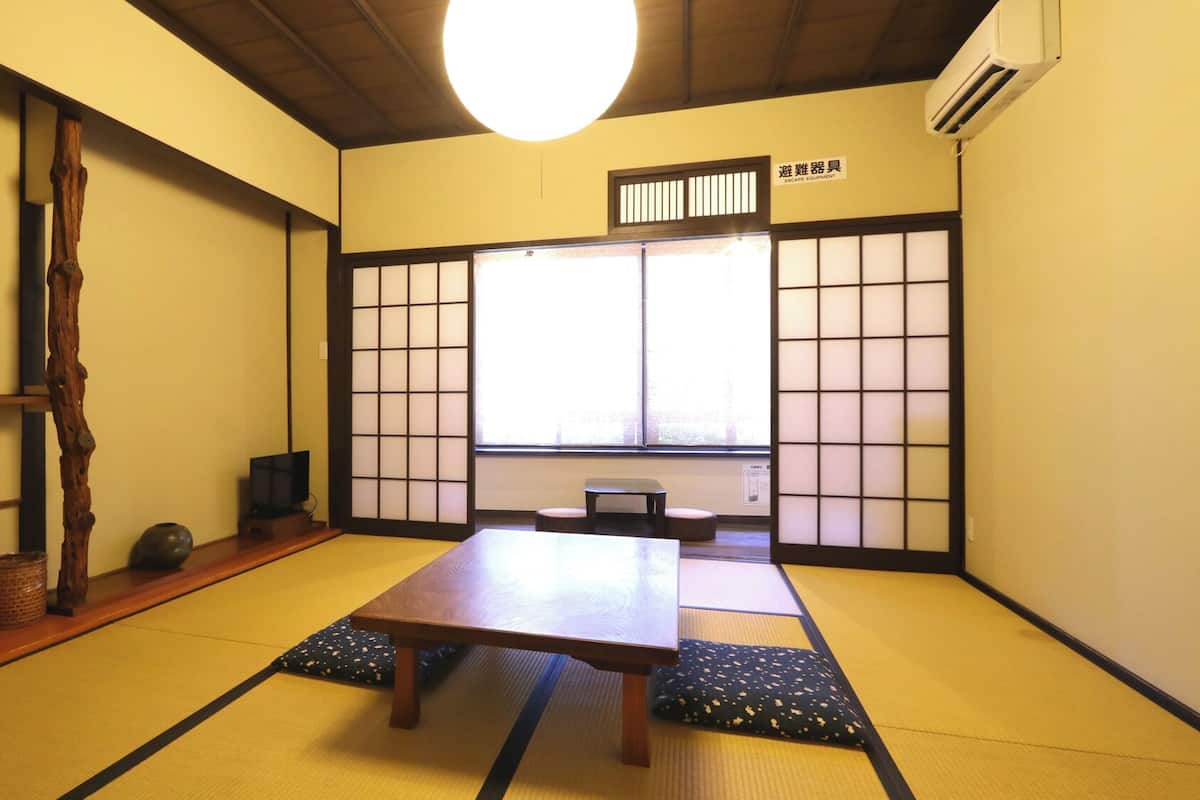 A traditional Japanese room with tatami flooring, a low table, and sliding doors.
