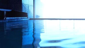 A pool with clear water reflecting light, surrounded by walls.