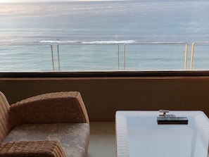Varanda com mobiliário de vime e mesa branca, com vista para o mar.
