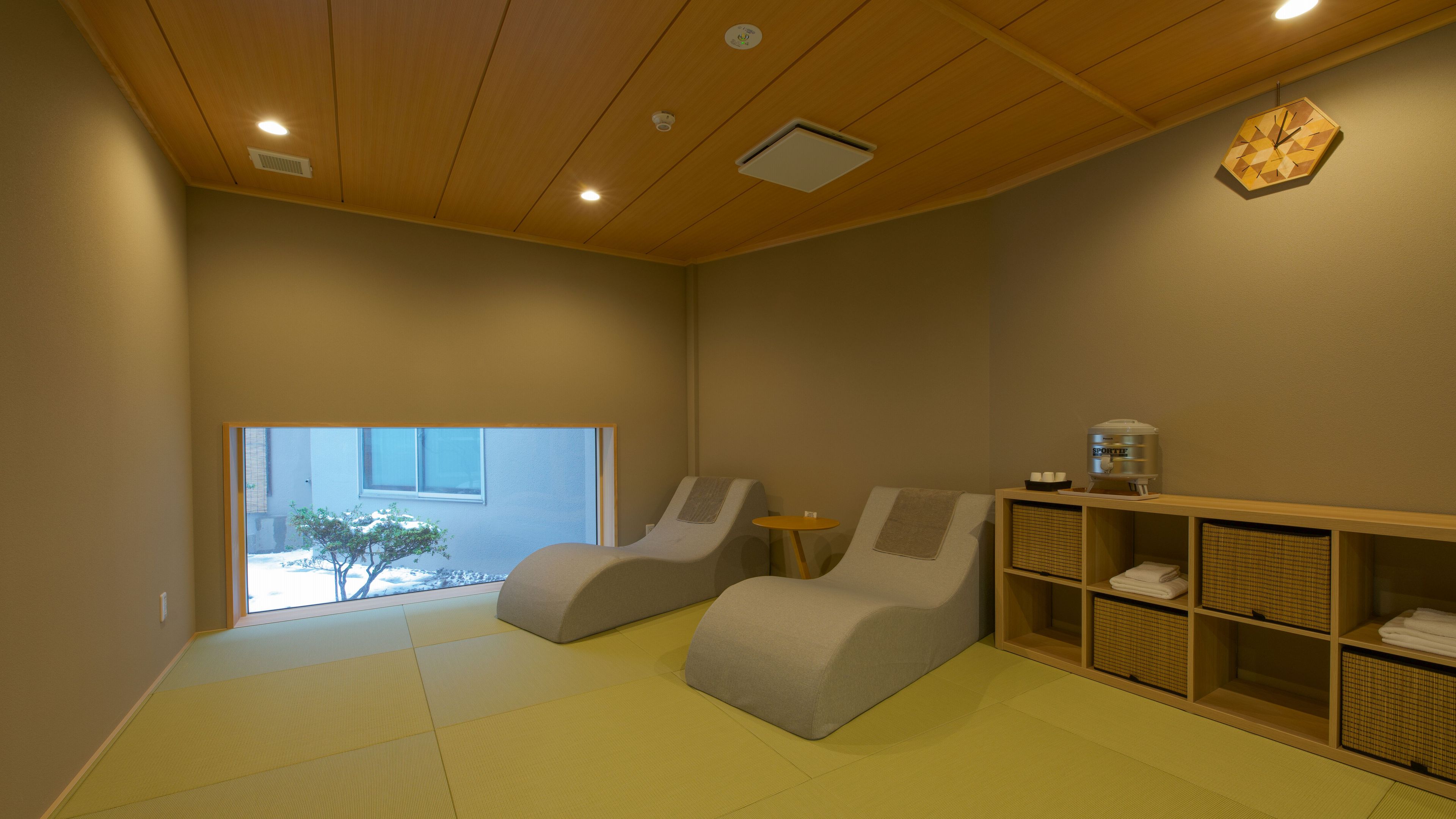 A room with tatami flooring, a water dispenser, and a view of a snowy landscape.