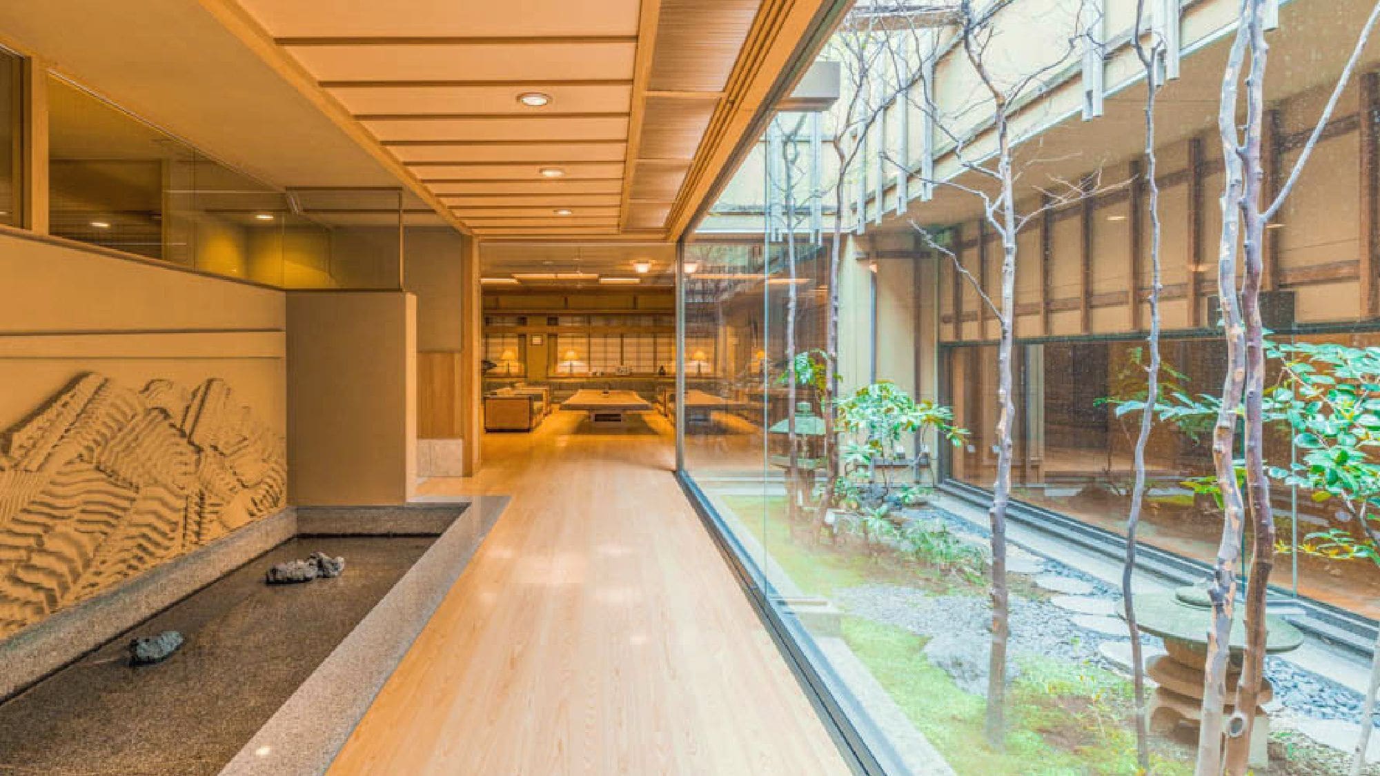 A modern interior with a long corridor, glass walls, and a view of a garden.