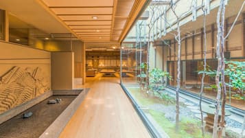 A modern interior with a long corridor, glass walls, and a view of a garden.