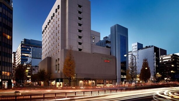 A modern building with a Courtyard by Marriott sign, surrounded by other high-rise buildings. - Courtyard by Marriott Tokyo Ginza (Matsushige)