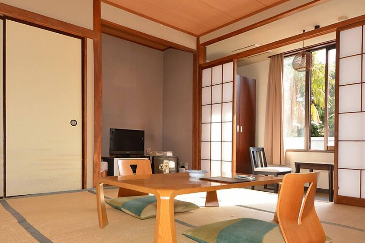 A traditional Japanese room with tatami flooring, a low table, and sliding doors.