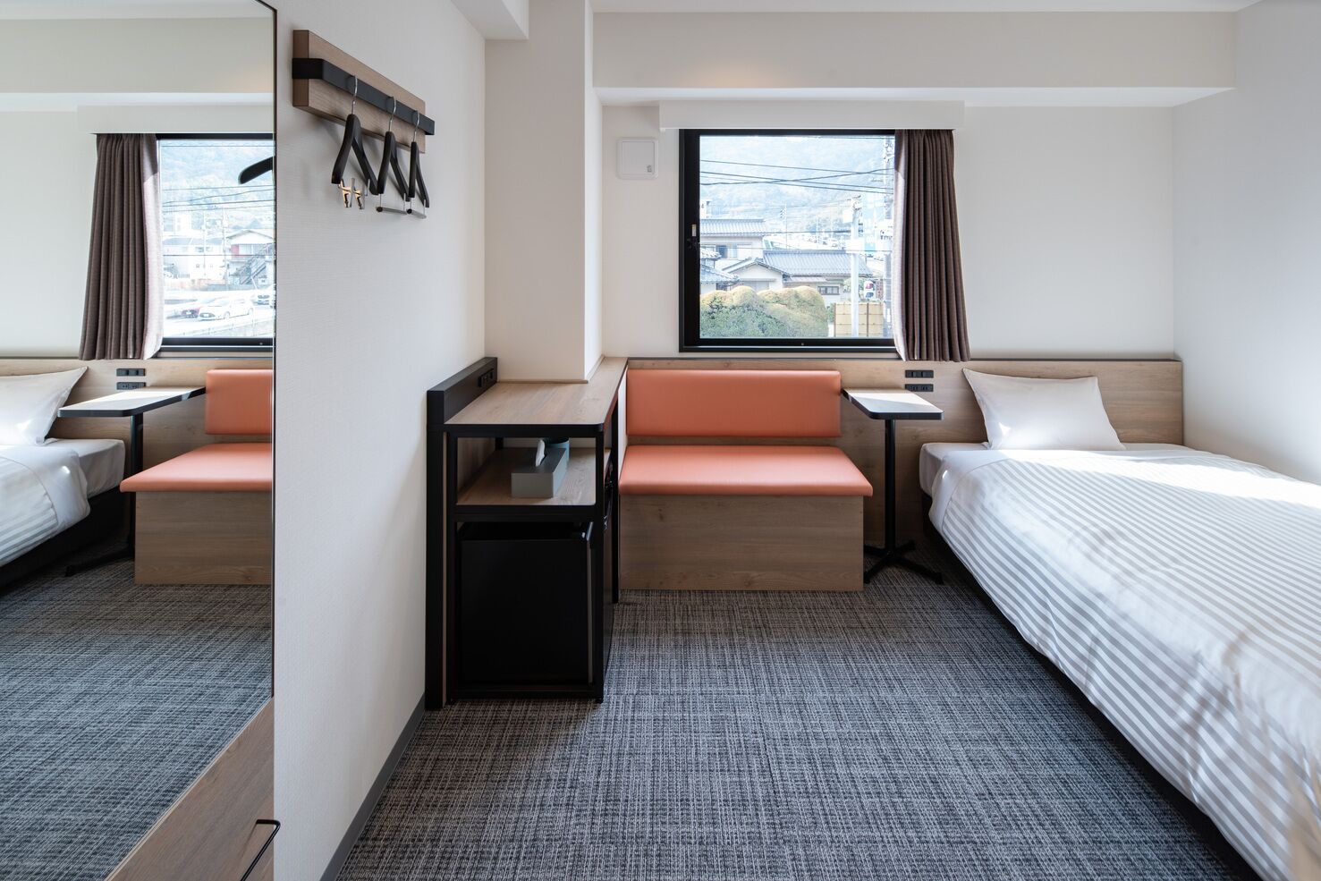 Una habitación de hotel con una cama, dos zonas de estar, una mesita y una ventana con cortinas.
