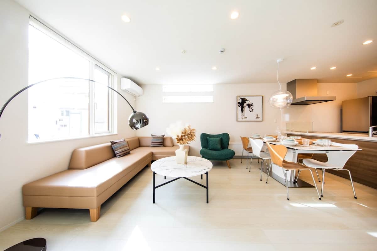 Un salon moderne comprenant un canapé, une table basse ronde et un coin repas avec des chaises et une table.