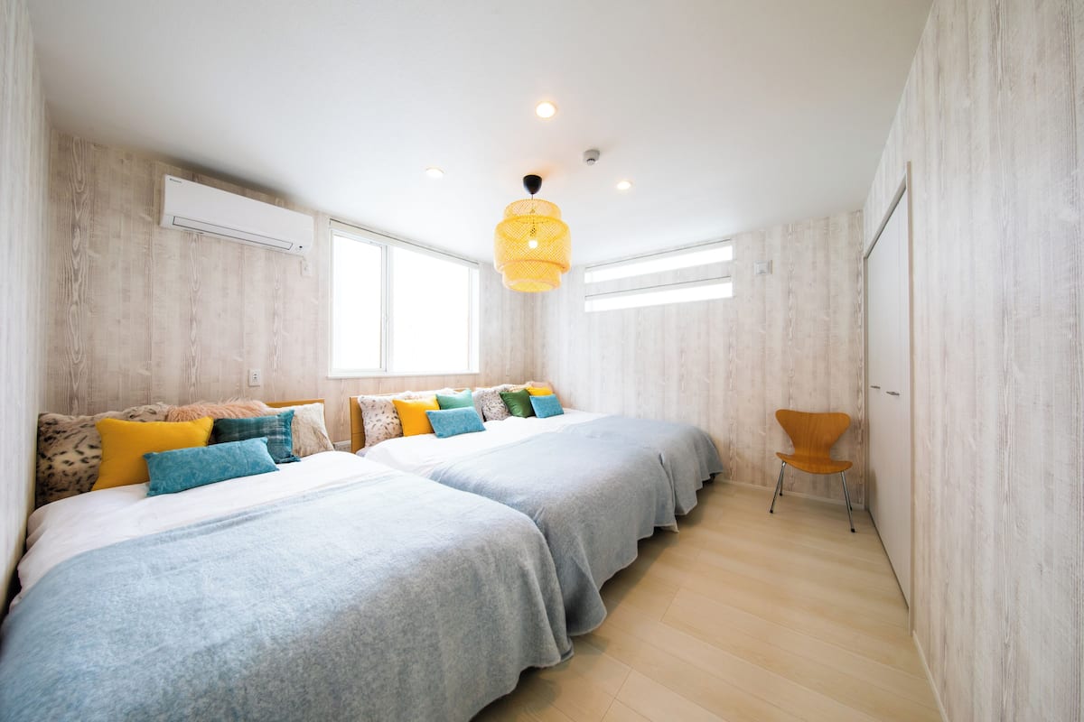 Une chambre avec deux lits, un luminaire suspendu et une fenêtre.