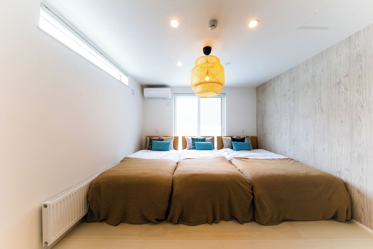 Une chambre à coucher avec un grand lit, une fenêtre et un luminaire au plafond.