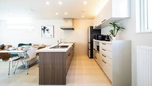 A modern kitchen with a central island, built-in appliances, and a dining area with chairs and a table. - Terrace Toyohira (Sapporo)