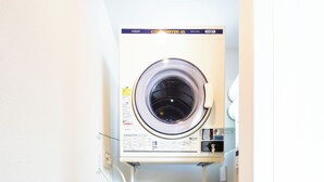 A compact, wall-mounted washer and dryer unit in a small laundry room. - Terrace Toyohira (Sapporo)