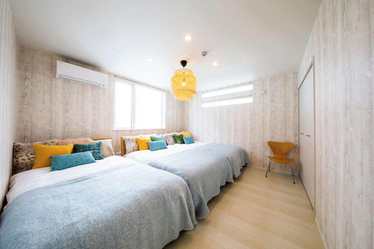 Un dormitorio con dos camas, una lámpara colgante y una ventana.