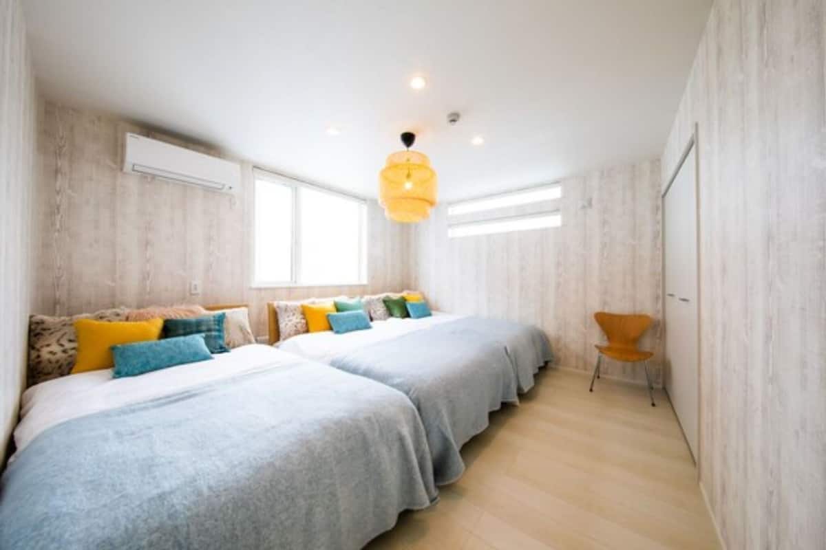 Une chambre avec deux lits, un luminaire suspendu et une fenêtre.