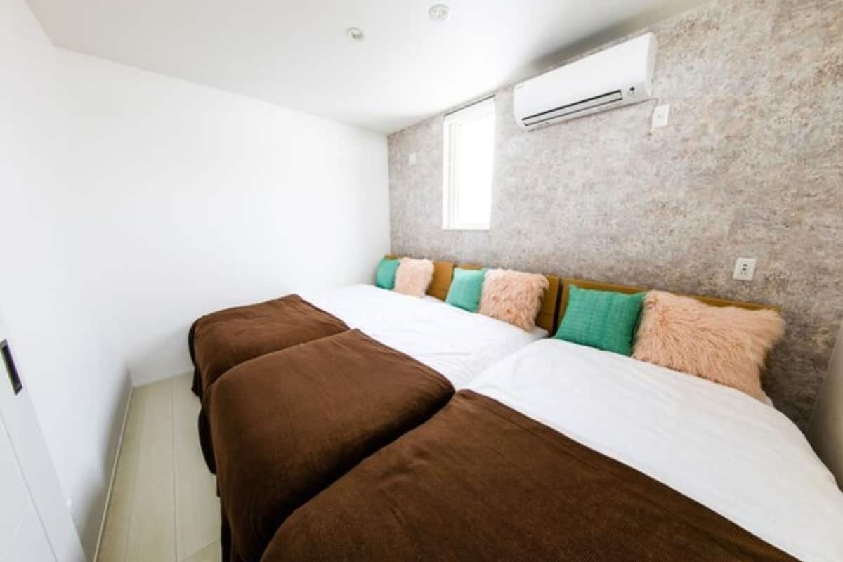 Une chambre à coucher avec un lit, des oreillers, un appareil de climatisation et une fenêtre.