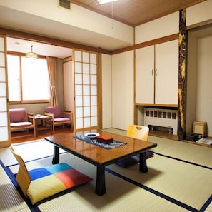 A traditional Japanese room with tatami flooring, a low table, and sliding doors.
