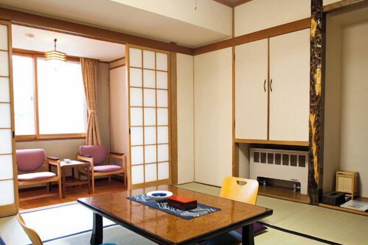 Ein traditioneller japanischer Raum mit Tatami-Böden, einem niedrigen Tisch und Schiebetüren.
