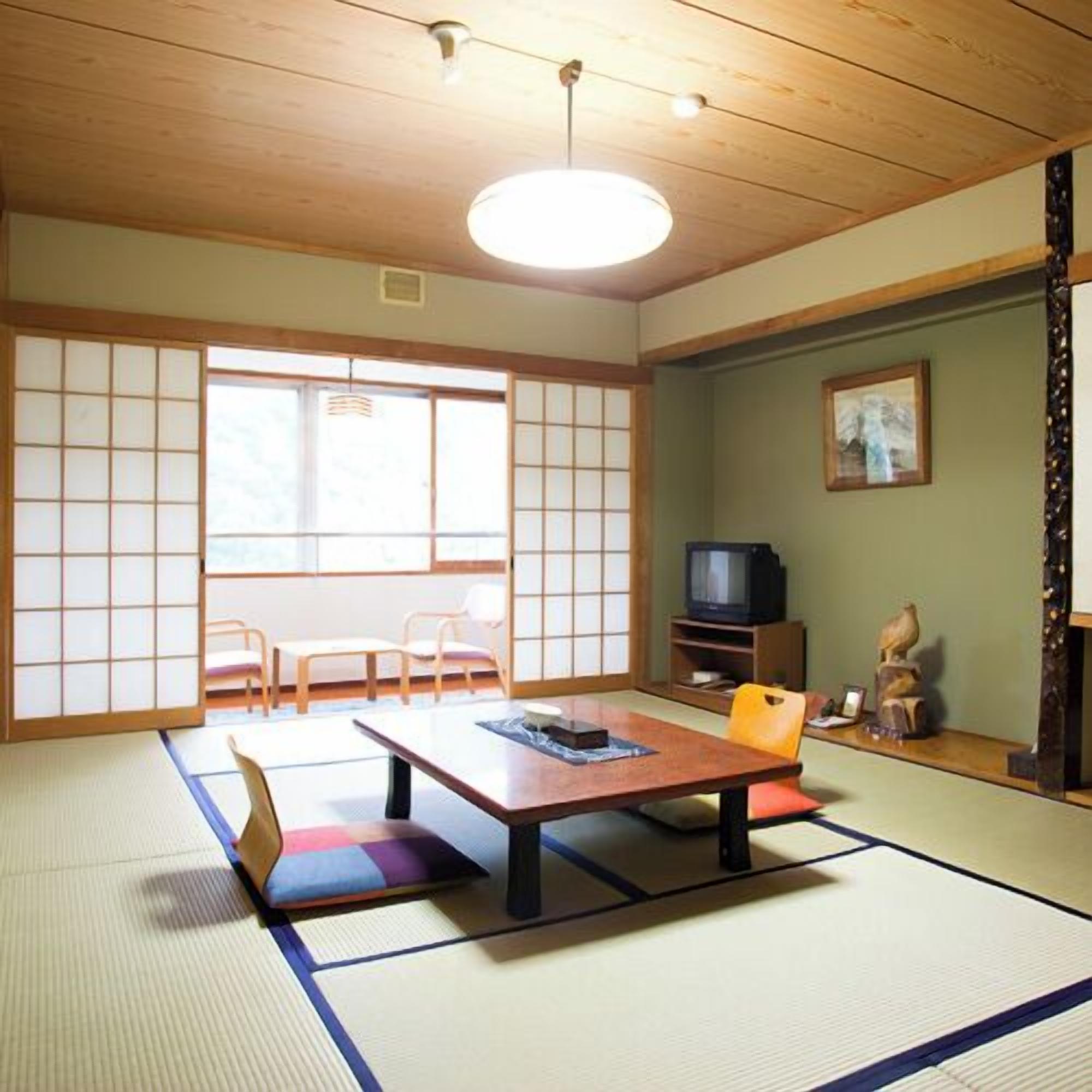 Une pièce de style japonais traditionnel, avec un sol recouvert de tatamis, une table basse et un téléviseur.