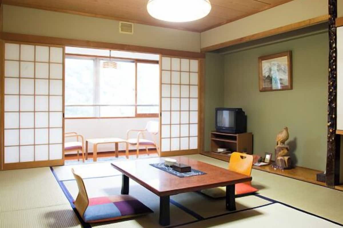 Une pièce de style japonais traditionnel, avec un sol recouvert de tatamis, une table basse et un téléviseur.